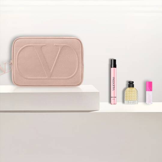 Valentino Beauty-Set: pinke Tasche, Parfums und Lippenprodukt auf Weiß.