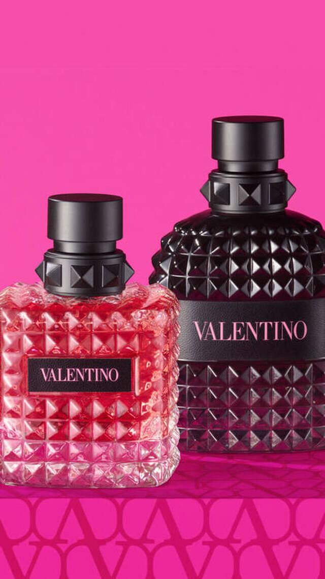 Zwei Parfumflaschen von Valentino auf einem pinken Hintergrund, eine in rosa und eine in schwarz, beide mit markantem, gepolstertem Design.